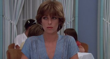 Movie still from “Summer Lovers” (1982), directed by Randal Kleiser – A person wearing a blue shirt; Close Up shot, Over the shoulder angle