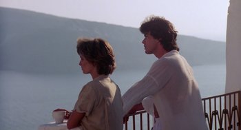 Movie still from “Summer Lovers” (1982), directed by Randal Kleiser – A man and a woman standing next to each other on a balcony; Medium shot, Over the shoulder angle