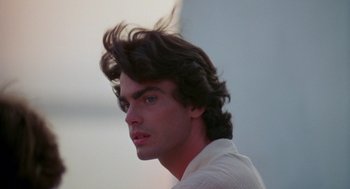 Movie still from “Summer Lovers” (1982), directed by Randal Kleiser – A person with long black hair; Close Up shot, Low angle
