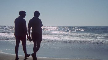 Movie still from “Summer of '42” (1971), directed by Robert Mulligan – Two people standing on the beach looking out at the ocean; Wide shot, High angle