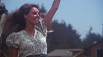 Movie still from “Summer of '42” (1971), directed by Robert Mulligan – A woman in a floral dress waves to the crowd; Medium shot, Low angle