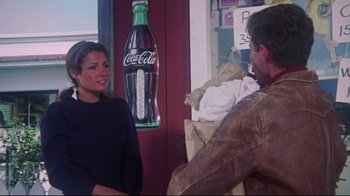 Movie still from “Summer of '42” (1971), directed by Robert Mulligan – A man and a woman talking in front of a coke sign; Medium shot, Over the shoulder angle