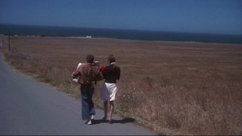Movie still from “Summer of '42” (1971), directed by Robert Mulligan – Two people walking down a road near the ocean; Wide shot, High angle