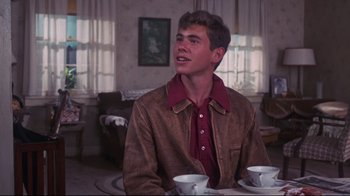Movie still from “Summer of '42” (1971), directed by Robert Mulligan – A man sitting at a table with two white cups; Medium shot, Over the shoulder angle