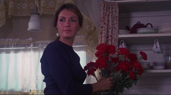 Movie still from “Summer of '42” (1971), directed by Robert Mulligan – A beautiful woman holding a bouquet of red flowers; Medium shot, Low angle