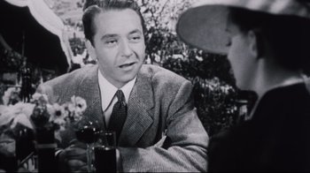 Movie still from “Summer of '42” (1971), directed by Robert Mulligan – An old photo of a man sitting at a table talking to another man; Close Up shot, Over the shoulder angle