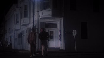 Movie still from “Summer of '42” (1971), directed by Robert Mulligan – Two men are standing in front of a barber shop at night; Wide shot, Low angle
