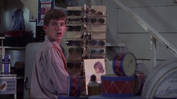 Movie still from “Summer of '42” (1971), directed by Robert Mulligan – A young man standing in front of a display of sunglasses; Close Up shot, Over the shoulder angle