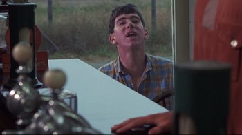 Movie still from “Summer of '42” (1971), directed by Robert Mulligan – A man sitting at a dining table with his mouth open; Medium shot, Over the shoulder angle