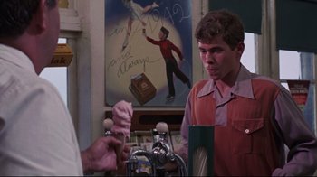 Movie still from “Summer of '42” (1971), directed by Robert Mulligan – A man in an orange and red shirt is looking at a painting; Medium shot, Over the shoulder angle