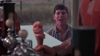Movie still from “Summer of '42” (1971), directed by Robert Mulligan – A young man holding an ice cream cone in front of a mirror; Close Up shot, Over the shoulder angle