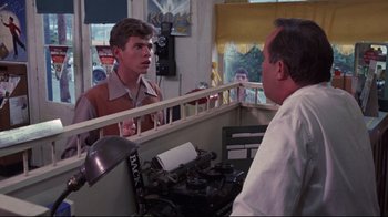 Movie still from “Summer of '42” (1971), directed by Robert Mulligan – A man is looking in the mirror at another man; Medium shot, Over the shoulder angle