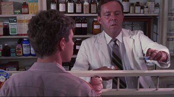 Movie still from “Summer of '42” (1971), directed by Robert Mulligan – A man in a white lab coat talking to a man in a brown shirt; Medium shot, Over the shoulder angle