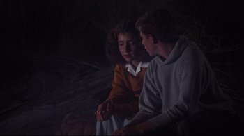 Movie still from “Summer of '42” (1971), directed by Robert Mulligan – A couple of people that are sitting on the ground together; Medium shot, Over the shoulder angle