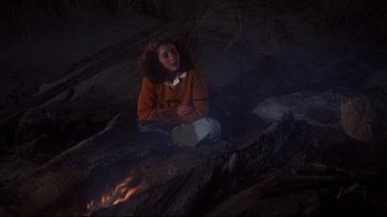 Movie still from “Summer of '42” (1971), directed by Robert Mulligan – A woman sitting on the ground near a fire; Medium shot, High angle