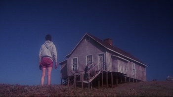 Movie still from “Summer of '42” (1971), directed by Robert Mulligan – A person standing in front of an old house; Wide shot, Low angle