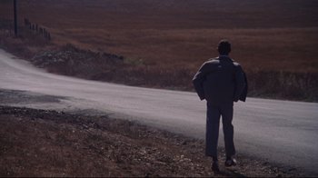 Movie still from “Summer of '42” (1971), directed by Robert Mulligan – A man standing on the side of a road near a field; Wide shot, High angle
