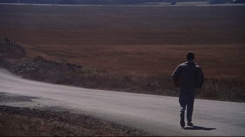 Movie still from “Summer of '42” (1971), directed by Robert Mulligan – A man riding a skateboard down the side of a dirt road; Extreme Wide shot, High angle