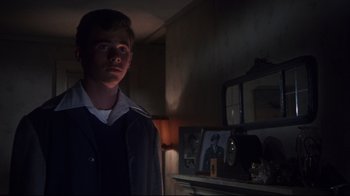 Movie still from “Summer of '42” (1971), directed by Robert Mulligan – A young man standing in a dark room; Medium shot, Over the shoulder angle