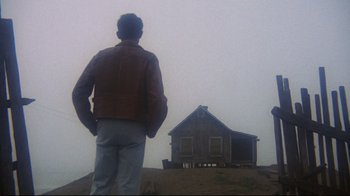Movie still from “Summer of '42” (1971), directed by Robert Mulligan – A man standing on top of a hill near a house; Wide shot, Low angle
