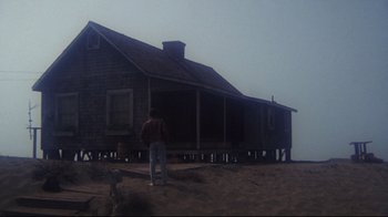 Movie still from “Summer of '42” (1971), directed by Robert Mulligan – A person standing in front of a house on the beach; Extreme Wide shot, Low angle