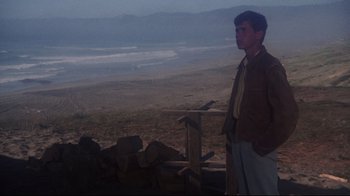 Movie still from “Summer of '42” (1971), directed by Robert Mulligan – A man standing on top of a dirt field; Wide shot, Low angle