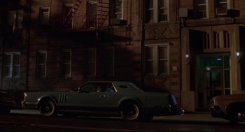 Movie still from “Summer of Sam” (1999), directed by Spike Lee – A car parked on the side of the road in front of a building; Extreme Wide shot, High angle
