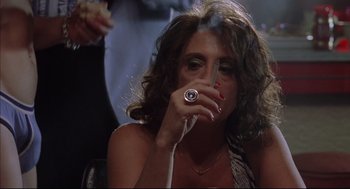 Movie still from “Summer of Sam” (1999), directed by Spike Lee – A woman smoking a cigarette while sitting in a chair; Close Up shot, Low angle
