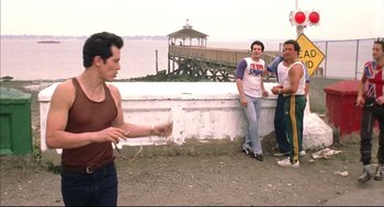 Movie still from “Summer of Sam” (1999), directed by Spike Lee – A group of men standing next to each other on a beach; Wide shot, Over the shoulder angle