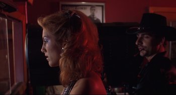Movie still from “Summer of Sam” (1999), directed by Spike Lee – A woman with red curly hair is standing in a room; Close Up shot, Over the shoulder angle