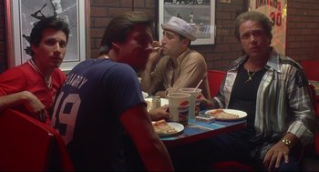 Movie still from “Summer of Sam” (1999), directed by Spike Lee – A group of men sitting at a table eating pizza; Medium shot, Over the shoulder angle