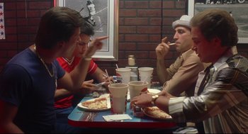 Movie still from “Summer of Sam” (1999), directed by Spike Lee – A group of people sitting at a table eating pizza; Medium shot, Over the shoulder angle