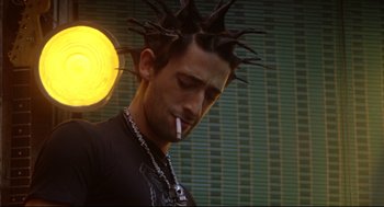 Movie still from “Summer of Sam” (1999), directed by Spike Lee – A man with spiky hair is smoking a cigarette; Close Up shot, Low angle