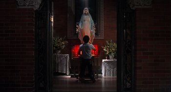 Movie still from “Summer of Sam” (1999), directed by Spike Lee – A man standing in front of a statue of mary; Wide shot, Low angle