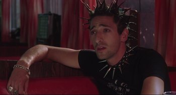 Movie still from “Summer of Sam” (1999), directed by Spike Lee – A man wearing a spiked collar sitting on a couch; Close Up shot, Low angle