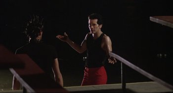 Movie still from “Summer of Sam” (1999), directed by Spike Lee – A man in a black tank top and red pants; Medium shot, Over the shoulder angle