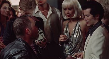 Movie still from “Summer of Sam” (1999), directed by Spike Lee – A woman in a silver dress talking to a man in a black suit; Medium shot, Over the shoulder angle