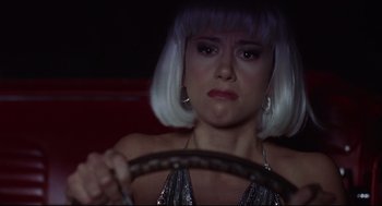 Movie still from “Summer of Sam” (1999), directed by Spike Lee – A woman with white hair is sitting in a car holding a steering wheel; Close Up shot, High angle