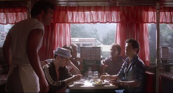 Movie still from “Summer of Sam” (1999), directed by Spike Lee – A group of men sitting at a table in a restaurant; Wide shot, Low angle