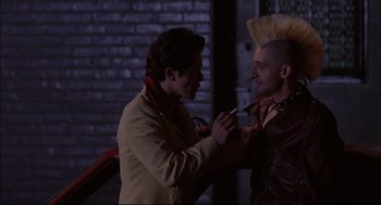 Movie still from “Summer of Sam” (1999), directed by Spike Lee – A man is shaving another man's face with an electric razor; Medium shot, Over the shoulder angle