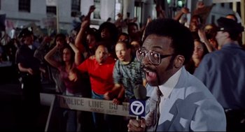 Movie still from “Summer of Sam” (1999), directed by Spike Lee – A man with a microphone in front of a group of onlookers; Medium shot, Low angle