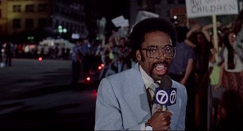 Movie still from “Summer of Sam” (1999), directed by Spike Lee – A man in a blue suit is holding a microphone; Medium shot, Low angle