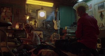 Movie still from “Summer of Sam” (1999), directed by Spike Lee – Two people sitting on a bed in a room with guitars; Wide shot, Low angle