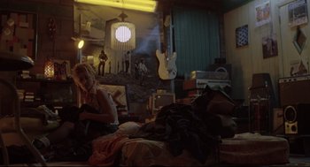 Movie still from “Summer of Sam” (1999), directed by Spike Lee – A woman sitting on a bed in front of a guitar; Wide shot, Low angle