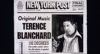 Movie still from “Summer of Sam” (1999), directed by Spike Lee – An old new york post newspaper with a man holding a cell phone; Close Up shot, Overhead angle