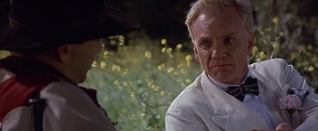Movie still from “Sunset” (1988), directed by Blake Edwards – A man and a woman are sitting in a field; Close Up shot, Over the shoulder angle