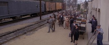 Movie still from “Sunset” (1988), directed by Blake Edwards – A group of people standing on a train track next to train tracks; Extreme Wide shot, High angle
