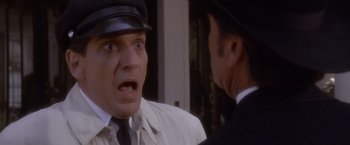Movie still from “Sunset” (1988), directed by Blake Edwards – A man in a hat and a suit is looking at another man; Close Up shot, Low angle