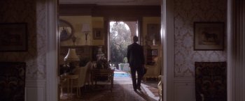 Movie still from “Sunset” (1988), directed by Blake Edwards – A man in a suit walking into a living room; Wide shot, Over the shoulder angle