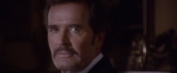 Movie still from “Sunset” (1988), directed by Blake Edwards – A man with a mustache wearing a suit; Close Up shot, Over the shoulder angle